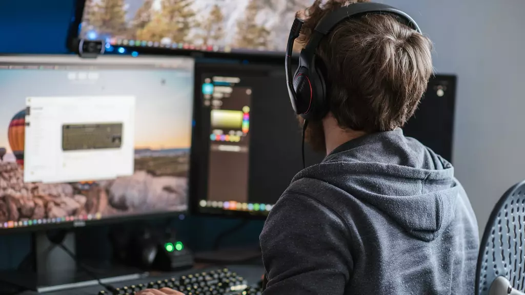 A developer with headphones, 3 monitors maybe coding a program
